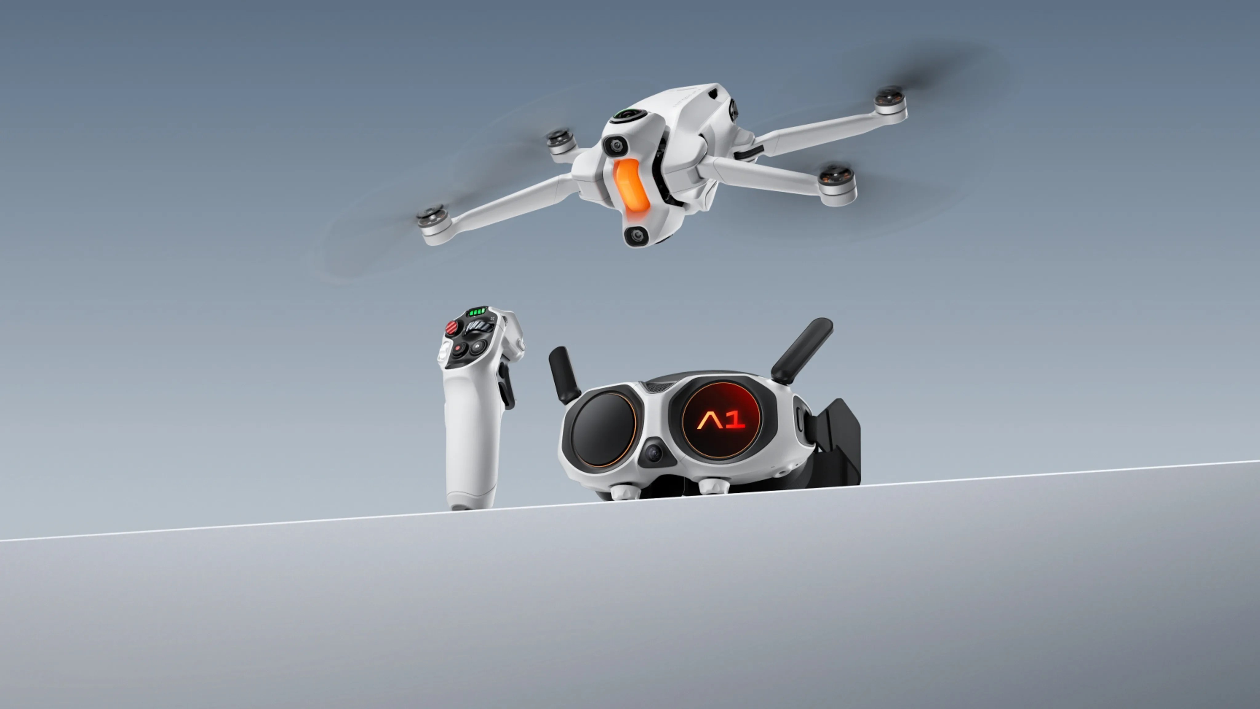 White quadcopter drone flying above a white remote controller and VR-style goggles with "A1" displayed on one lens.