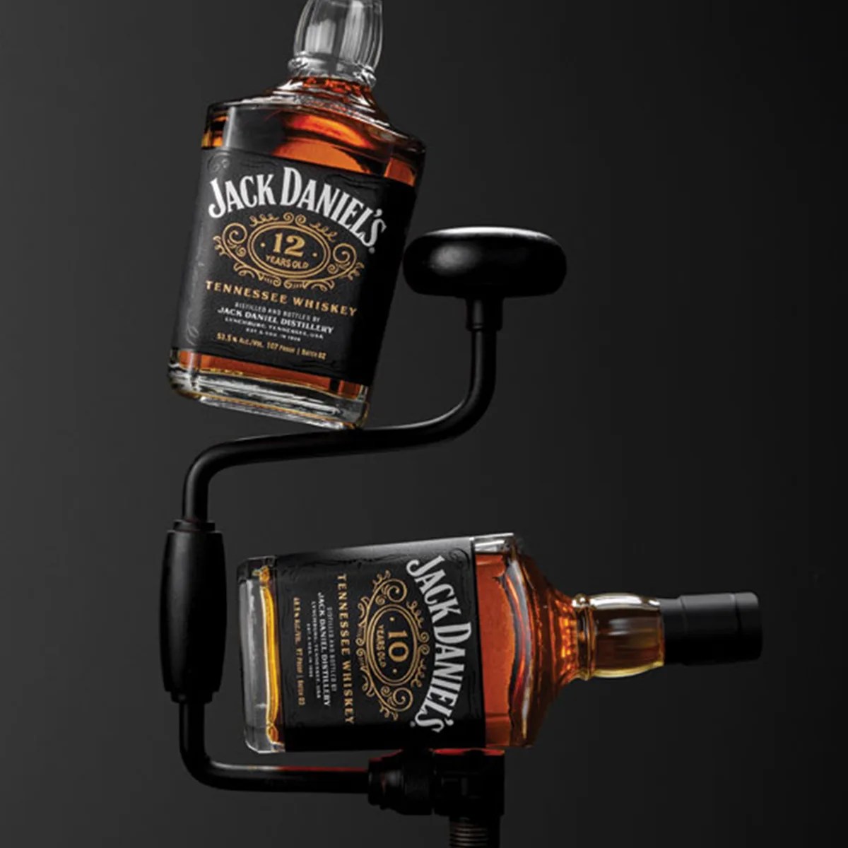 Two Jack Daniel's Tennessee Whiskey bottles, one 12 years old and one 10 years old, mounted on a black metal display stand.