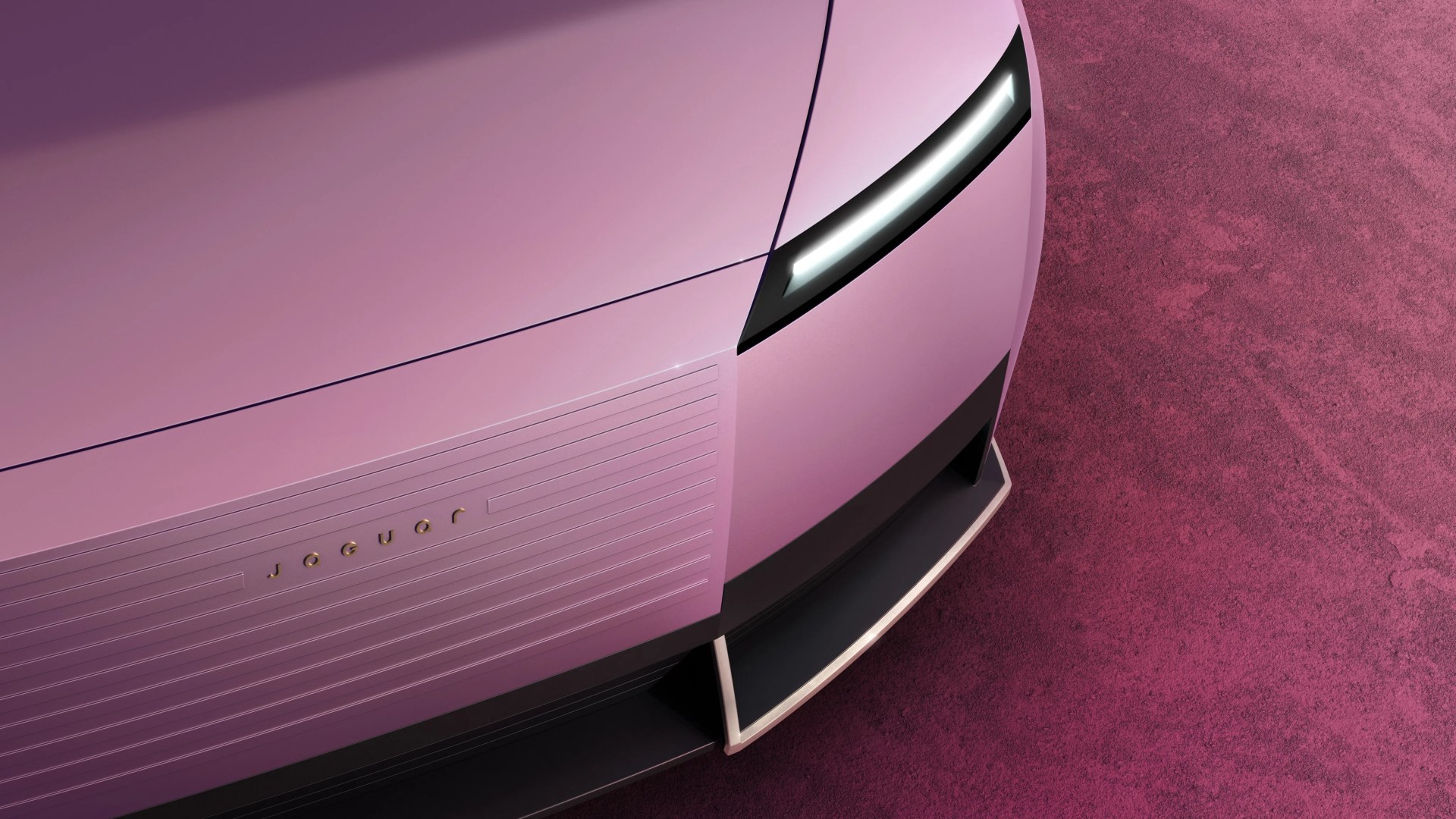 Close-up of the front end of a pink Jaguar car with sleek LED headlight and horizontal grille lines.