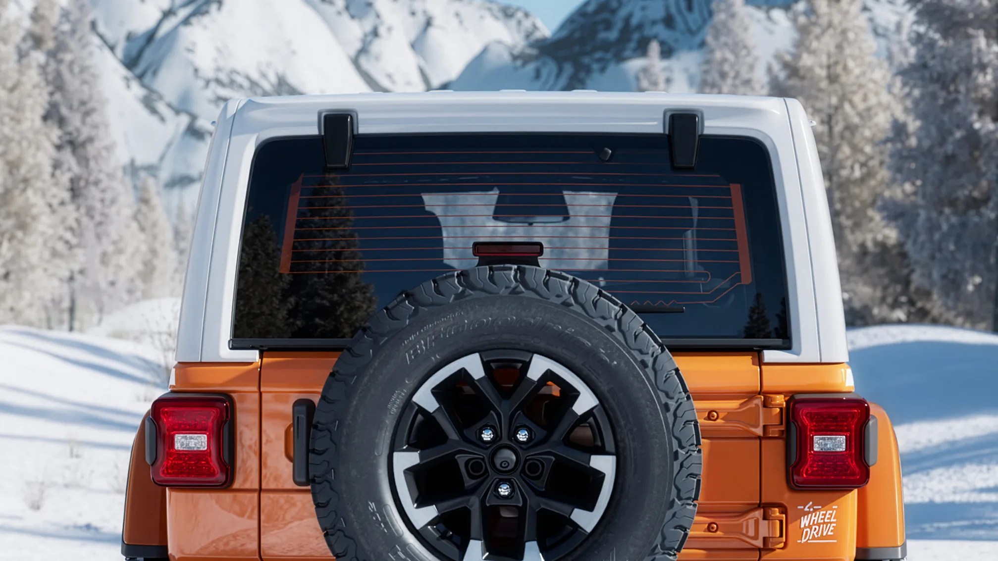 Rear view of an orange and white off-road vehicle with a spare tire mounted on the back in a snowy mountain setting.