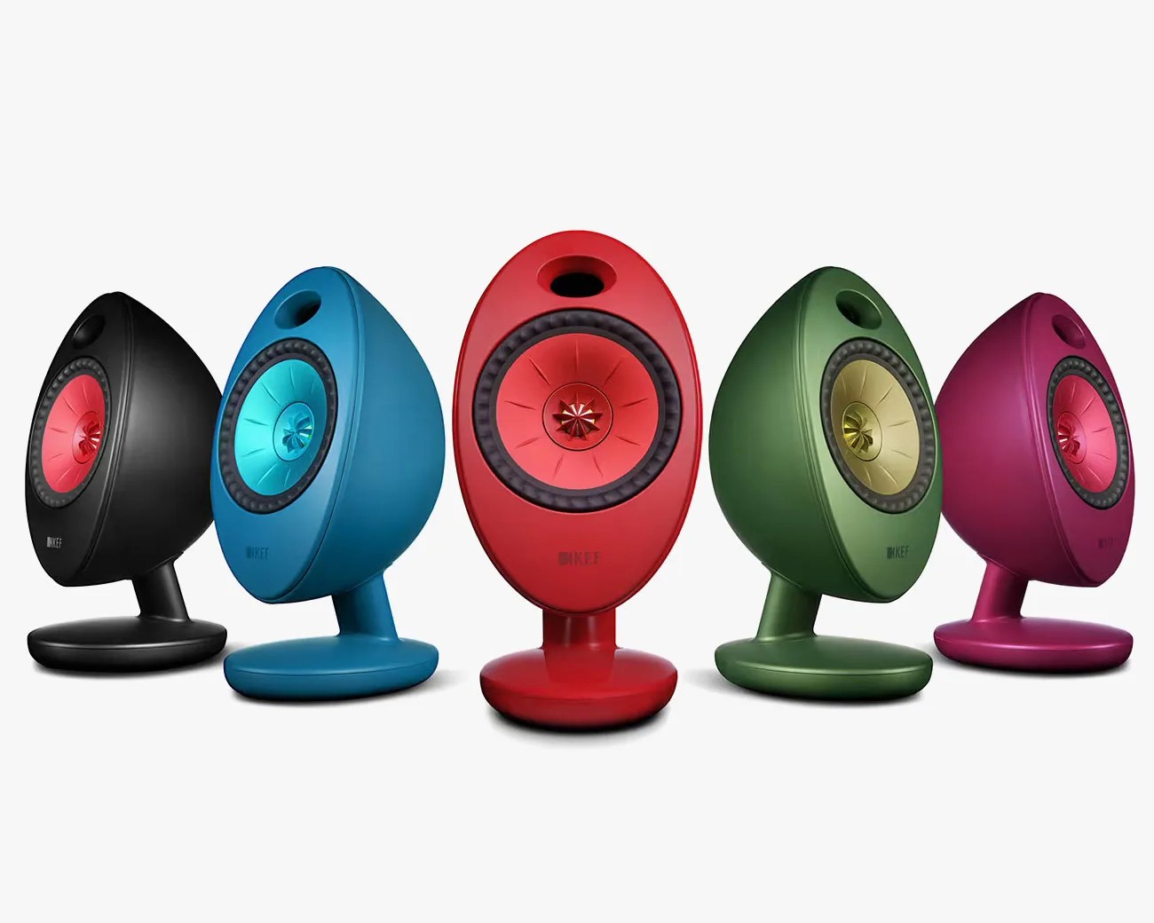 Five oval-shaped KEF speakers in black, blue, red, green, and purple with colorful central cones on round bases.