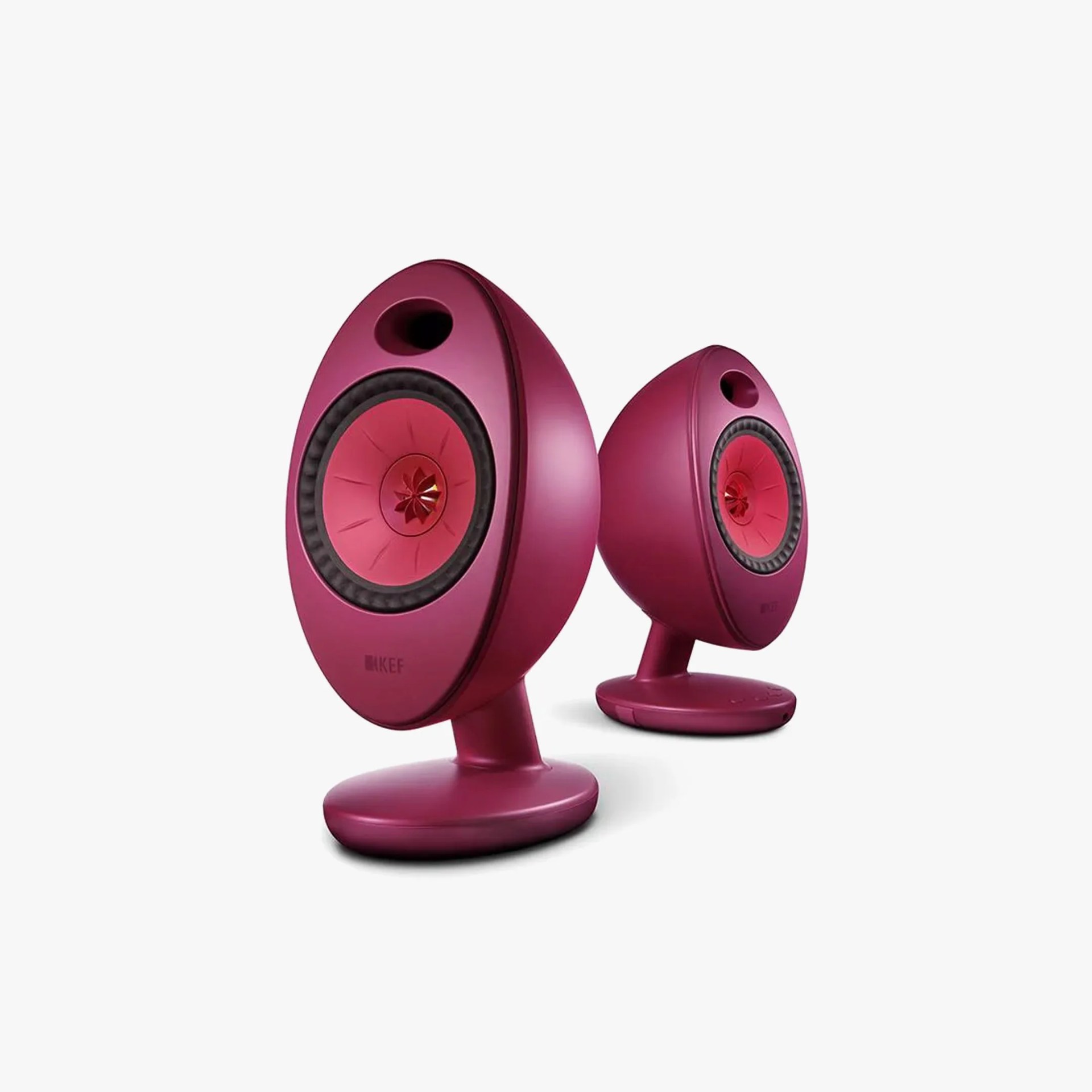 Pair of egg-shaped purple KEF speakers with red drivers on oval bases against white background.