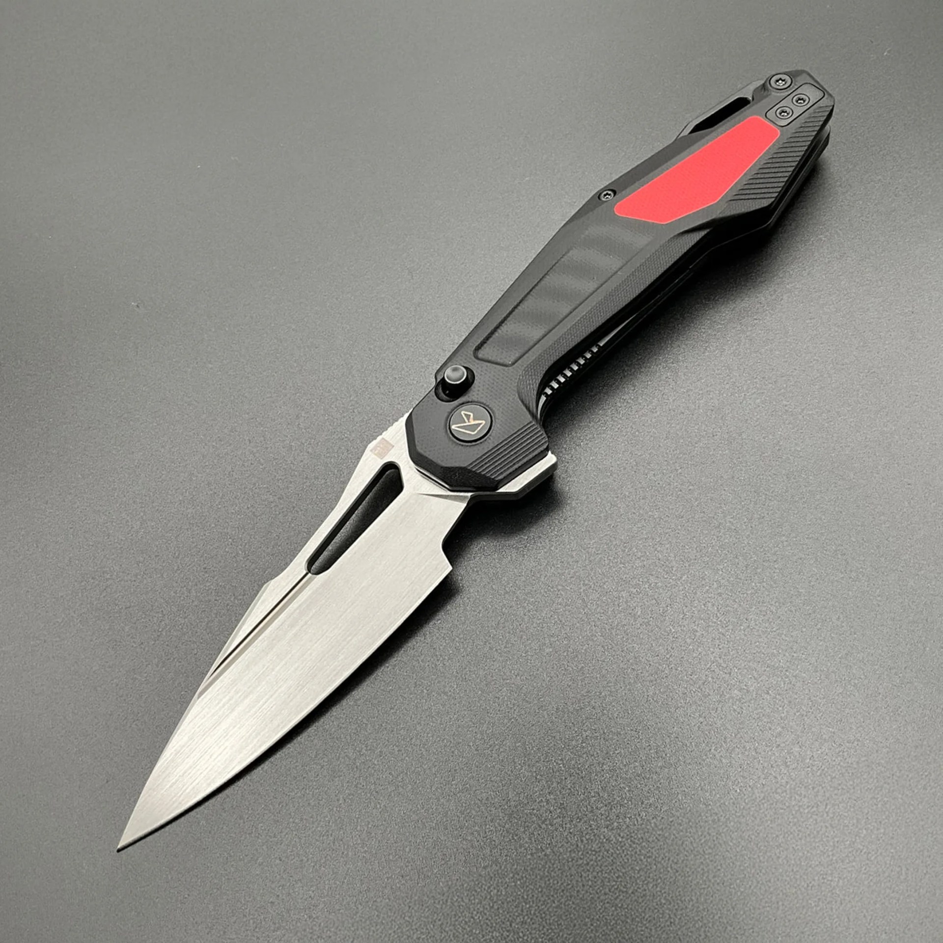 Folding knife with a silver blade and black handle featuring a red inlay and textured grip.