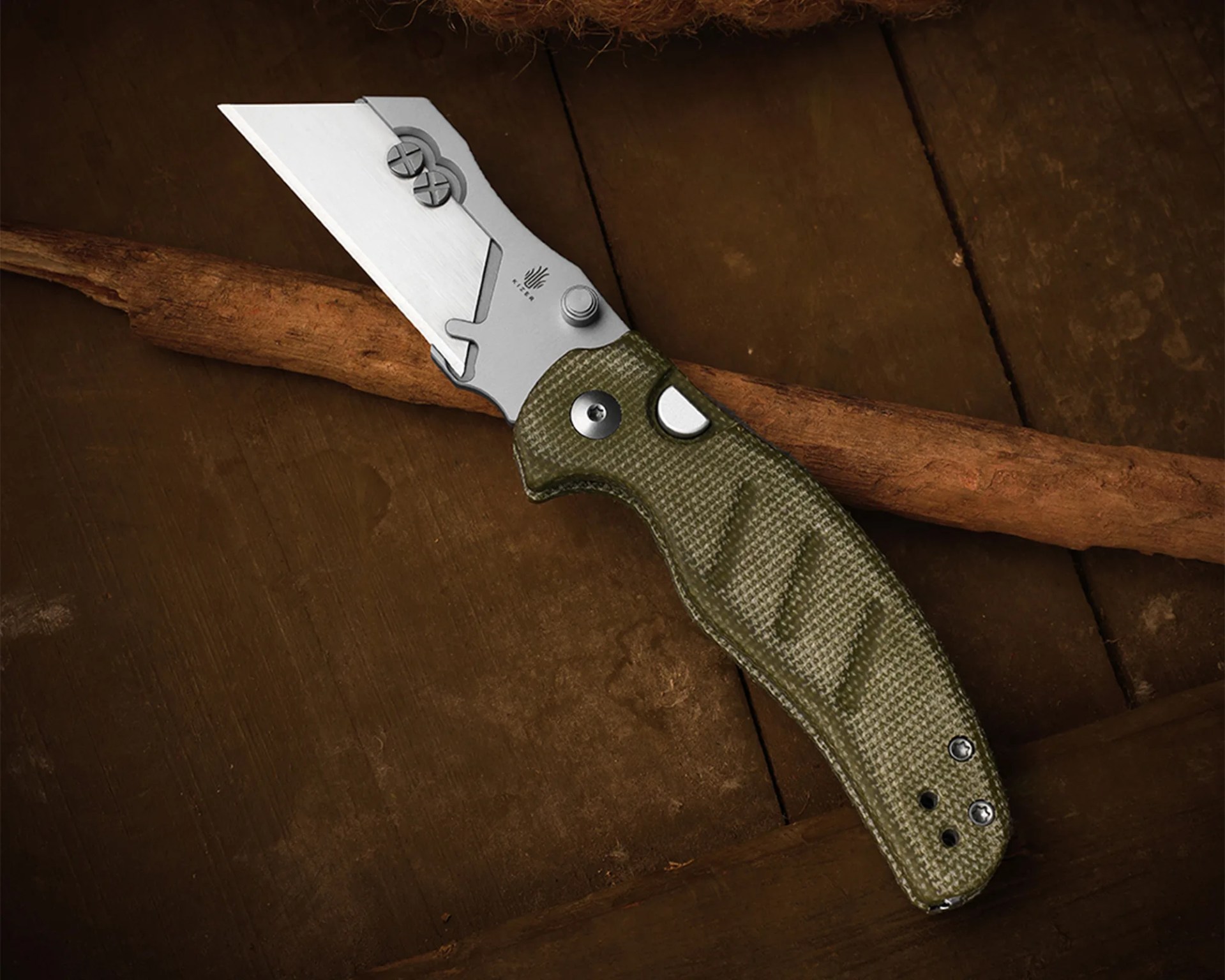 Folding knife with a silver tanto-style blade and textured olive green handle on a wooden surface.