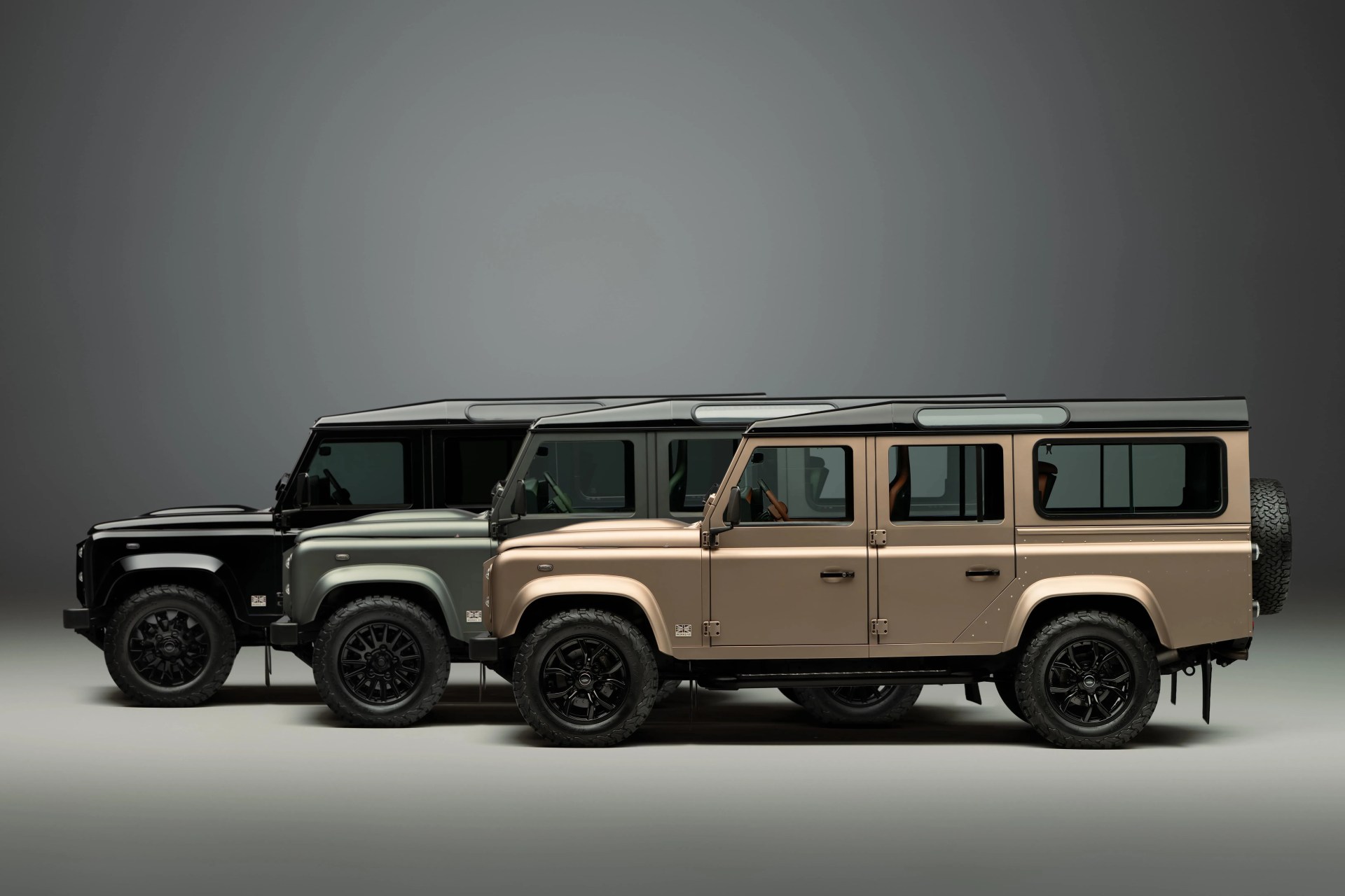 a lineup of classic land rover defenders arranged together on a studio backdrop