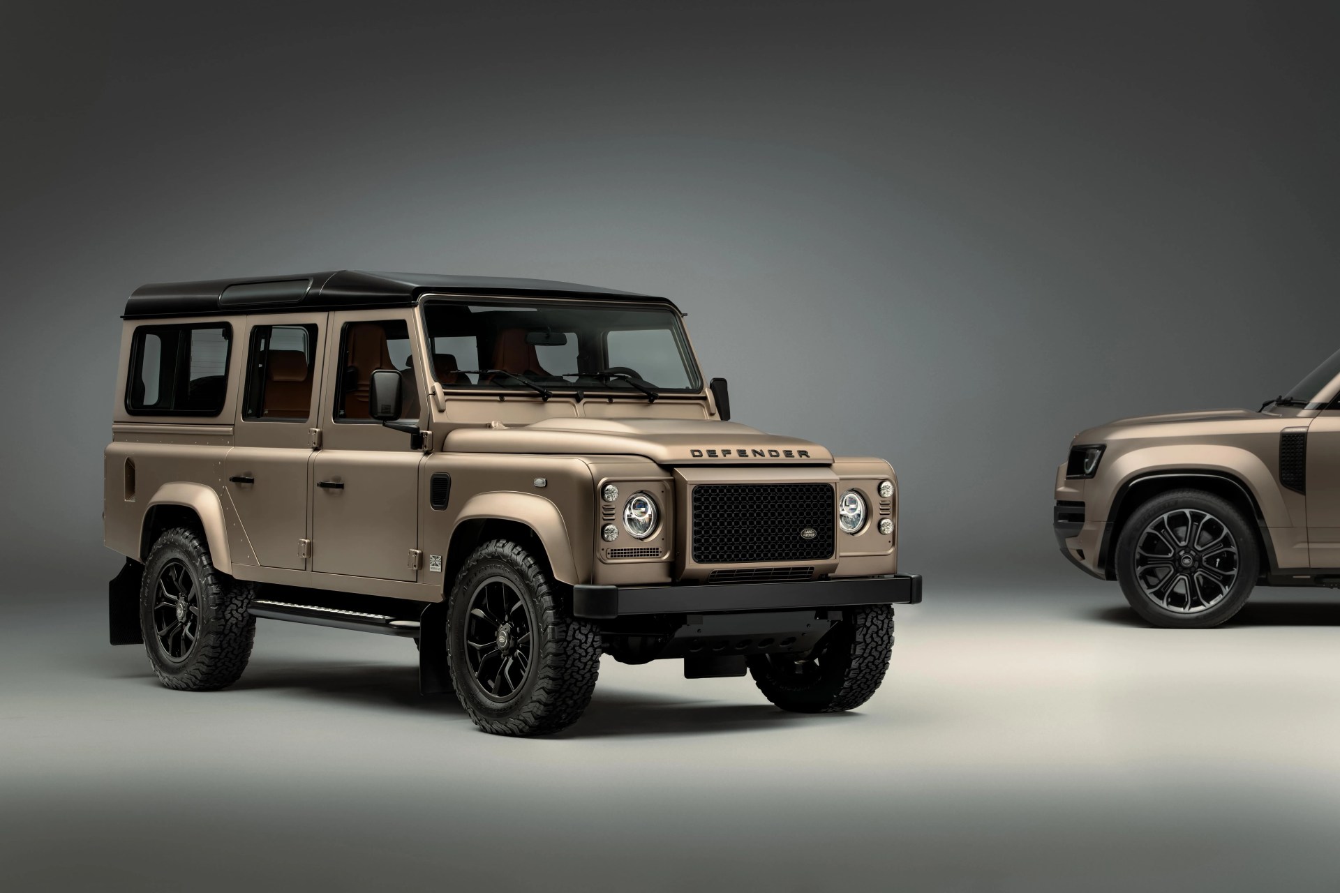 Matte beige Land Rover Defender 110 with black roof and wheels in a studio setting.