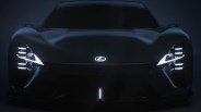 Front view of a sleek black Lexus sports car with illuminated logo and distinctive LED headlights in low light.
