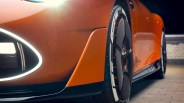 Close-up of an orange sports car's front wheel with Michelin tires and aerodynamic black and orange rims.