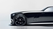 Front side view of a sleek black luxury car with a large black wheel featuring a Mercedes-Benz logo.