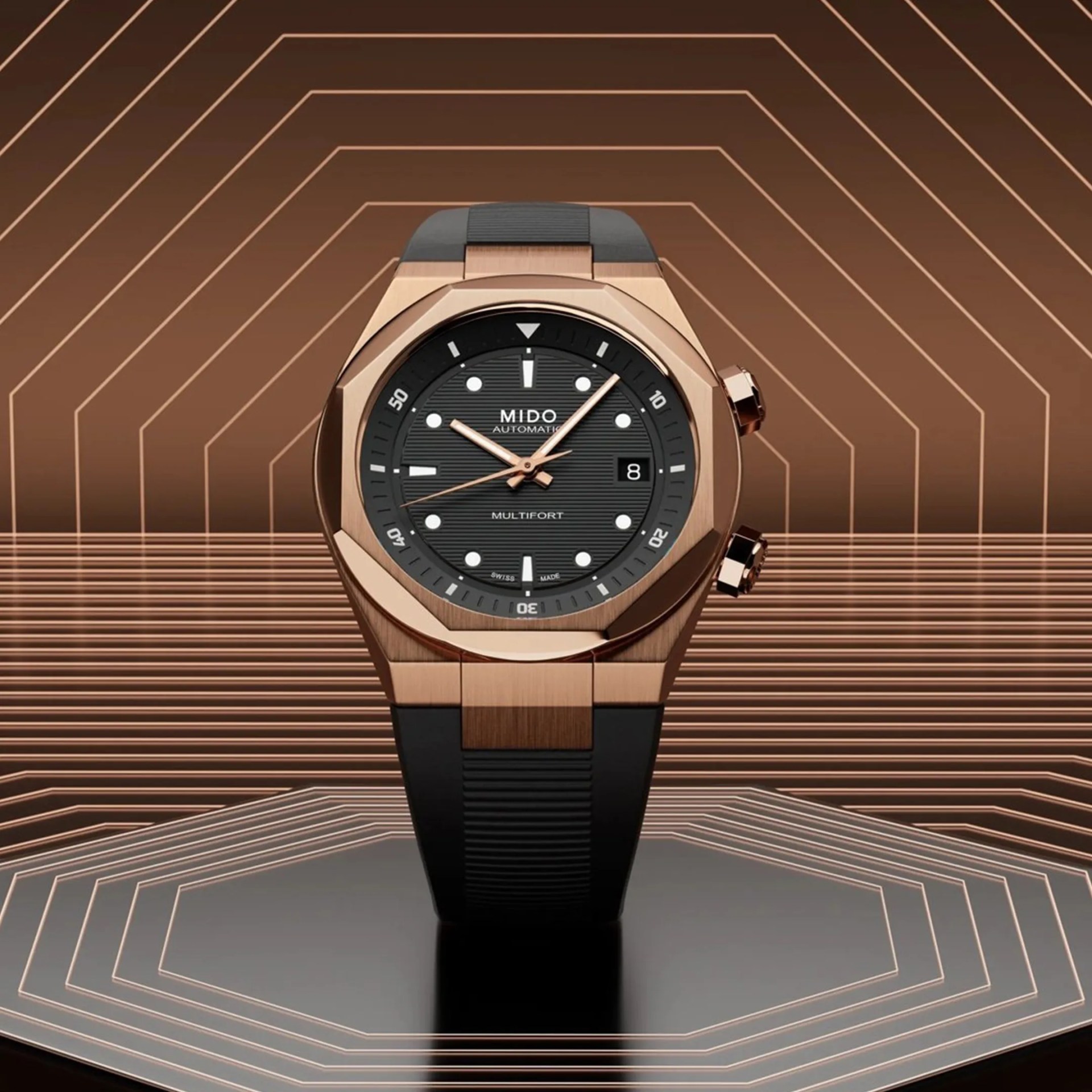 Rose gold and black Mido Multifort automatic wristwatch with black rubber strap on geometric brown background.