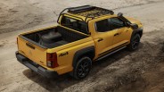 Yellow 4x4 pickup truck with black roof rack and snorkel on a dirt road.