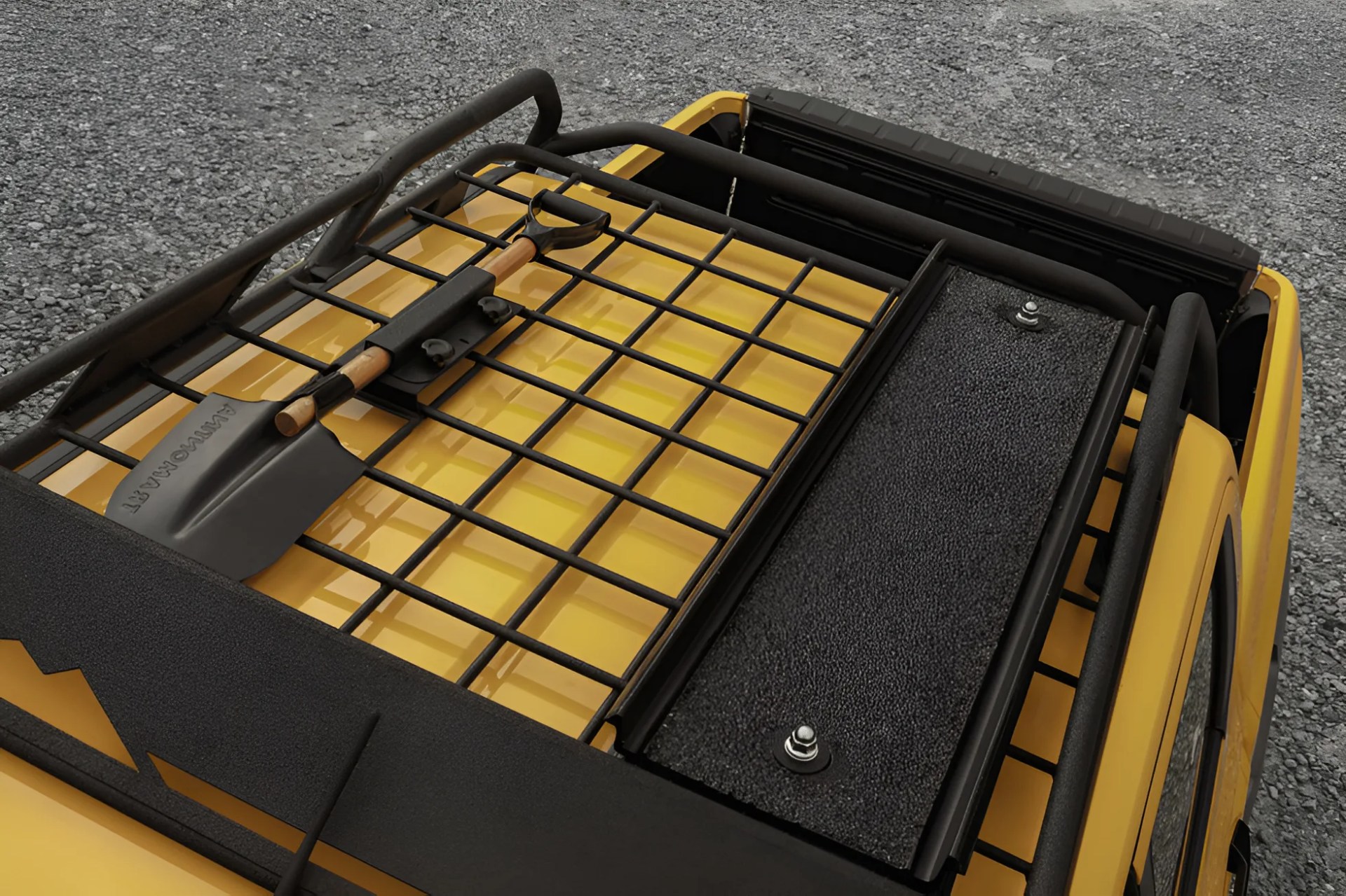 Black metal roof rack with grid pattern mounted on a yellow vehicle roof, holding a black shovel with a wooden handle.