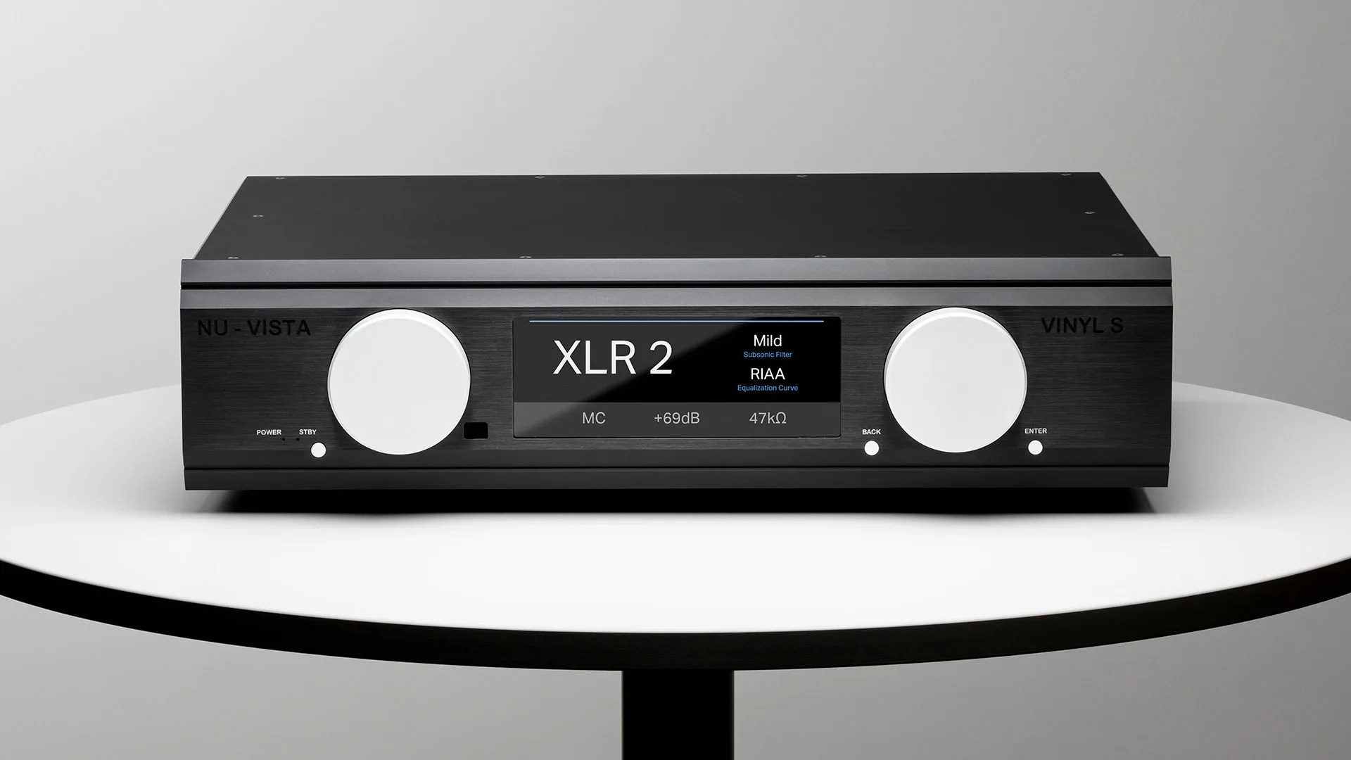 Black Nu-Vista Vinyl S audio preamplifier with two large white knobs and a digital display on a white round table.