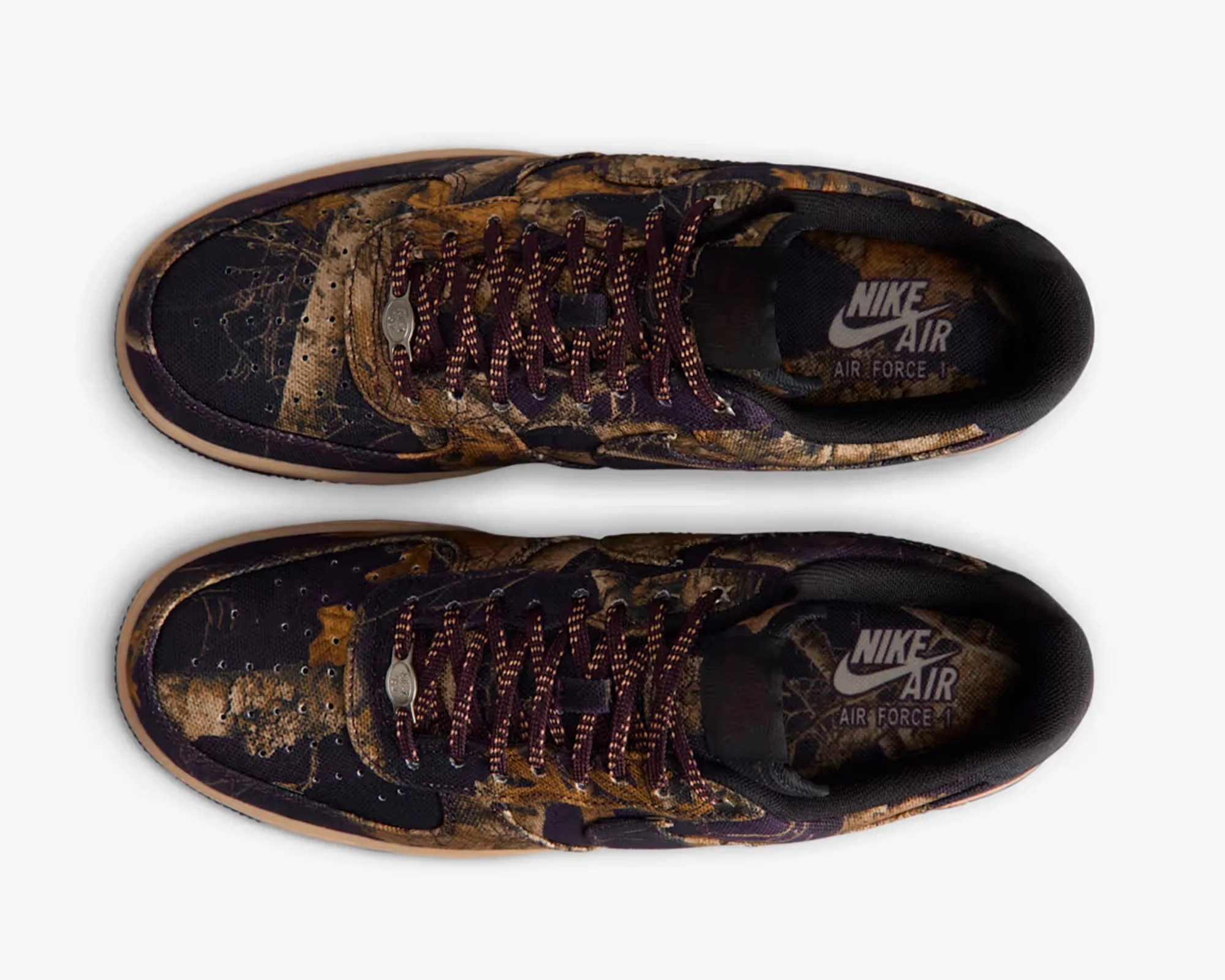 Pair of Nike Air Force 1 sneakers with brown and black camouflage pattern and maroon laces.
