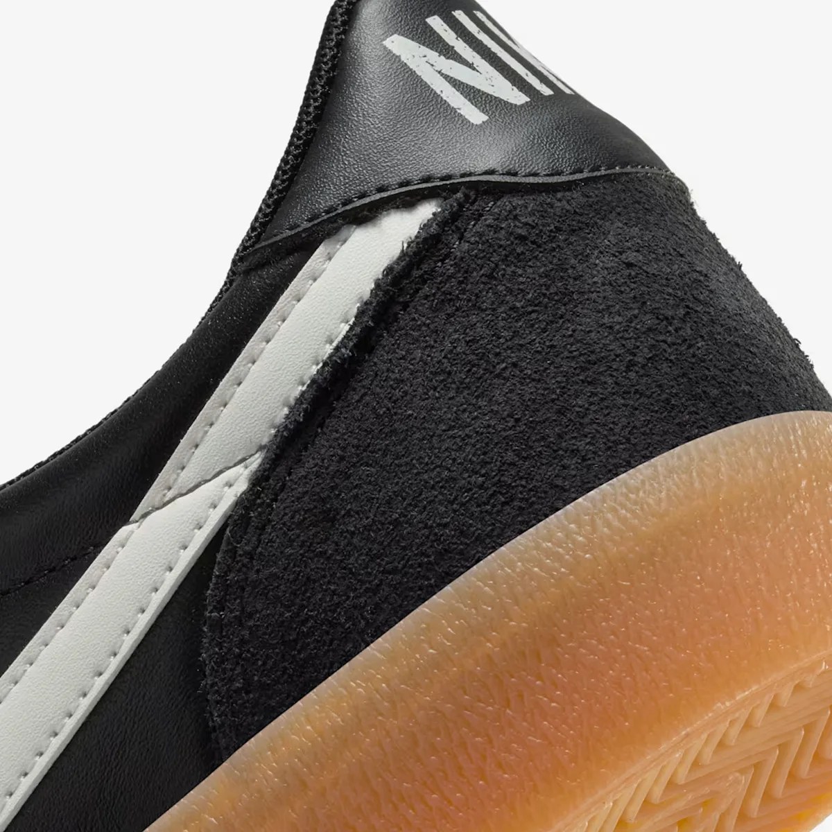 Close-up of black and white sneaker heel with textured gum sole and partial "NIKE" logo on black leather.