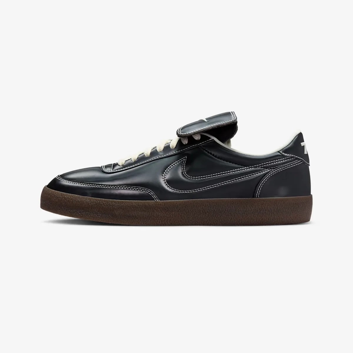 Black leather Nike sneaker with white stitching, cream laces, and a brown textured sole.