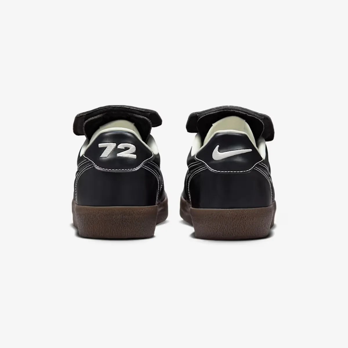 Pair of black Nike sneakers with white "72" on left heel and white Nike swoosh on right heel, brown soles.