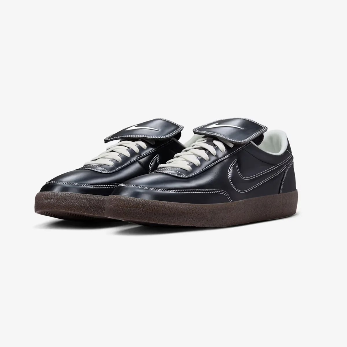 Pair of black leather Nike sneakers with white laces, white stitching, and brown rubber soles.