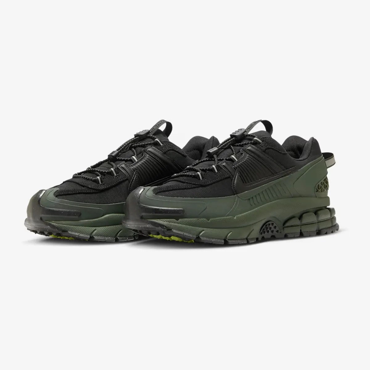 Pair of black and dark green athletic sneakers with textured soles and pull tabs on a white background.