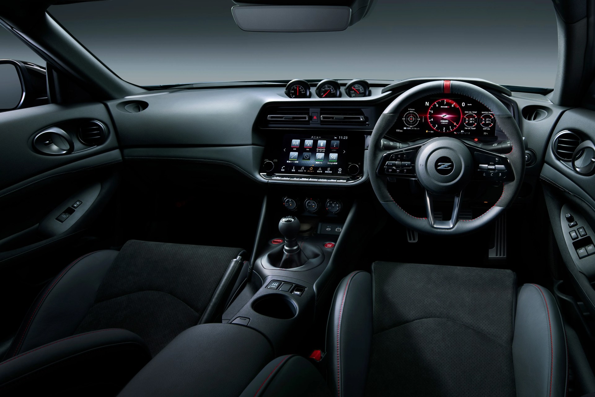 Black and gray car interior with digital dashboard, multifunction steering wheel, manual gear shift, and touchscreen center console.