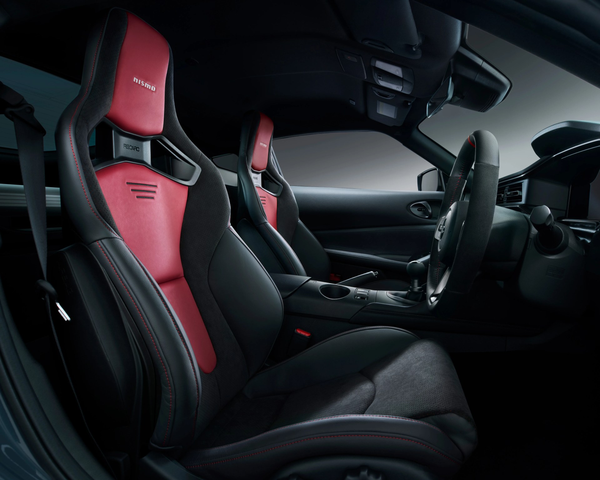 Black and red leather Recaro racing seats with "nismo" logo inside a car interior.