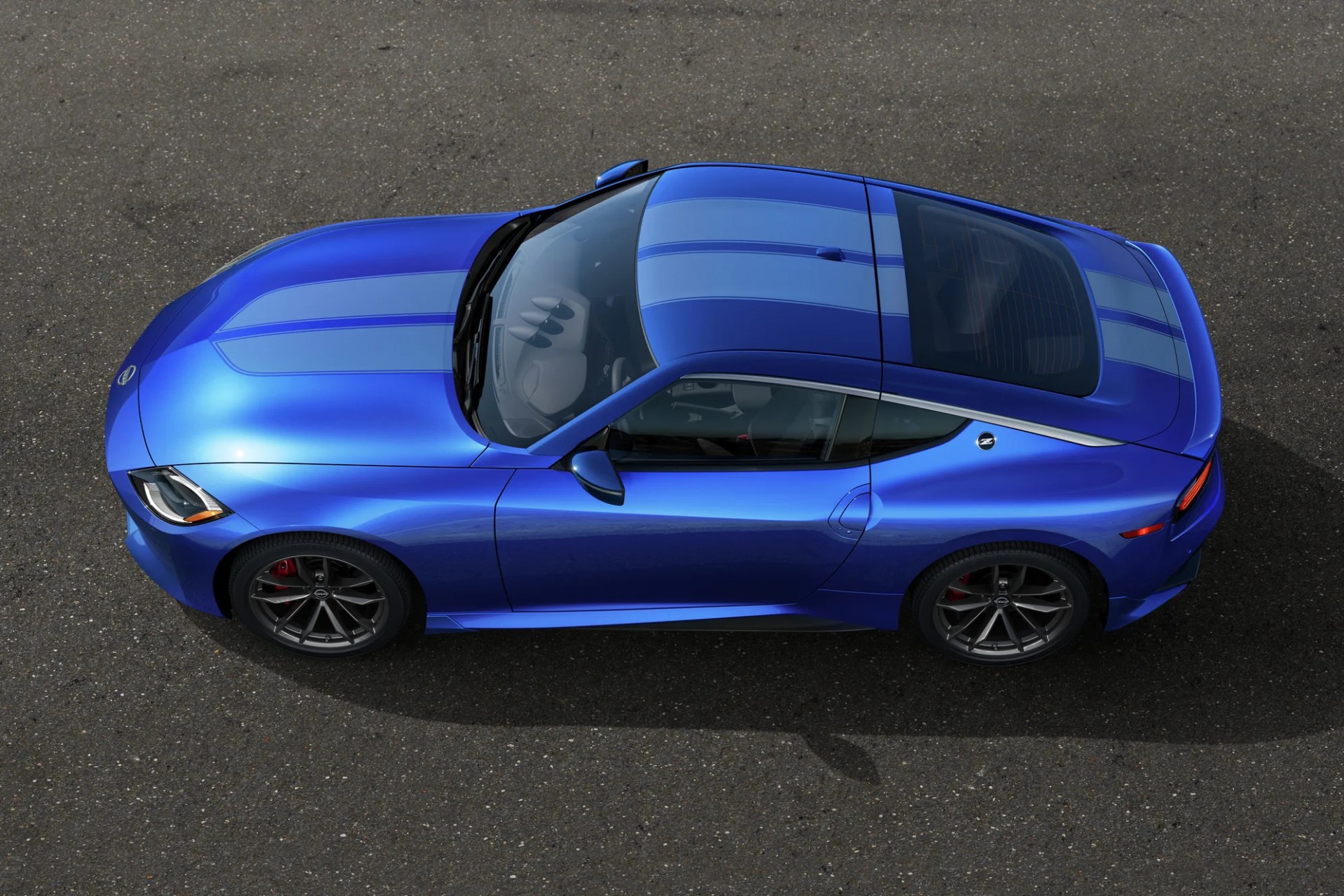 Blue sports car with light blue racing stripes viewed from above on asphalt.