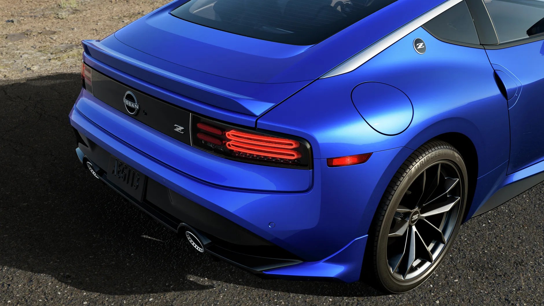 Rear side view of a blue Nissan Z sports car showing taillights, rear spoiler, and black alloy wheel.