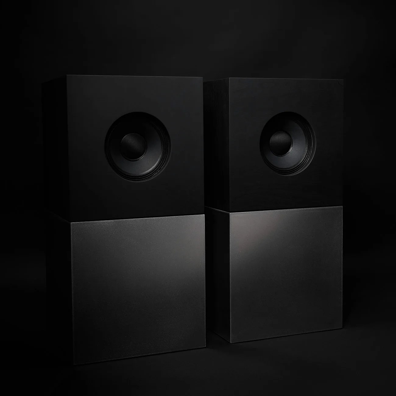 Pair of black rectangular speakers with a matte finish against a dark background.