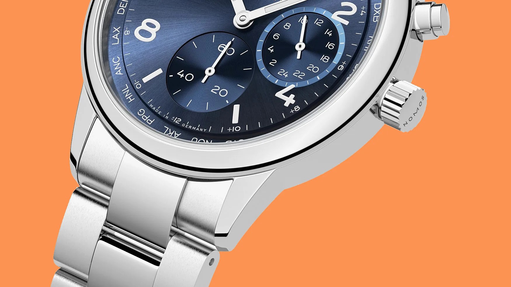 Close-up of a silver stainless steel watch with a blue dial and chronograph subdials on an orange background.
