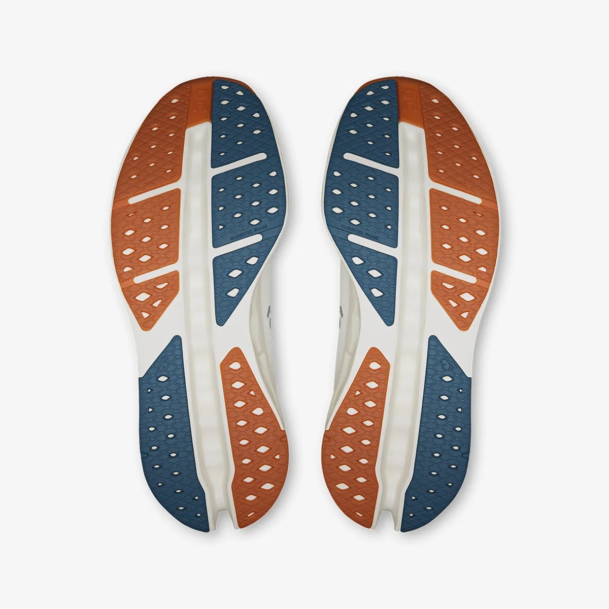 Pair of white shoe soles with blue and orange rubber traction pads, viewed from the bottom.