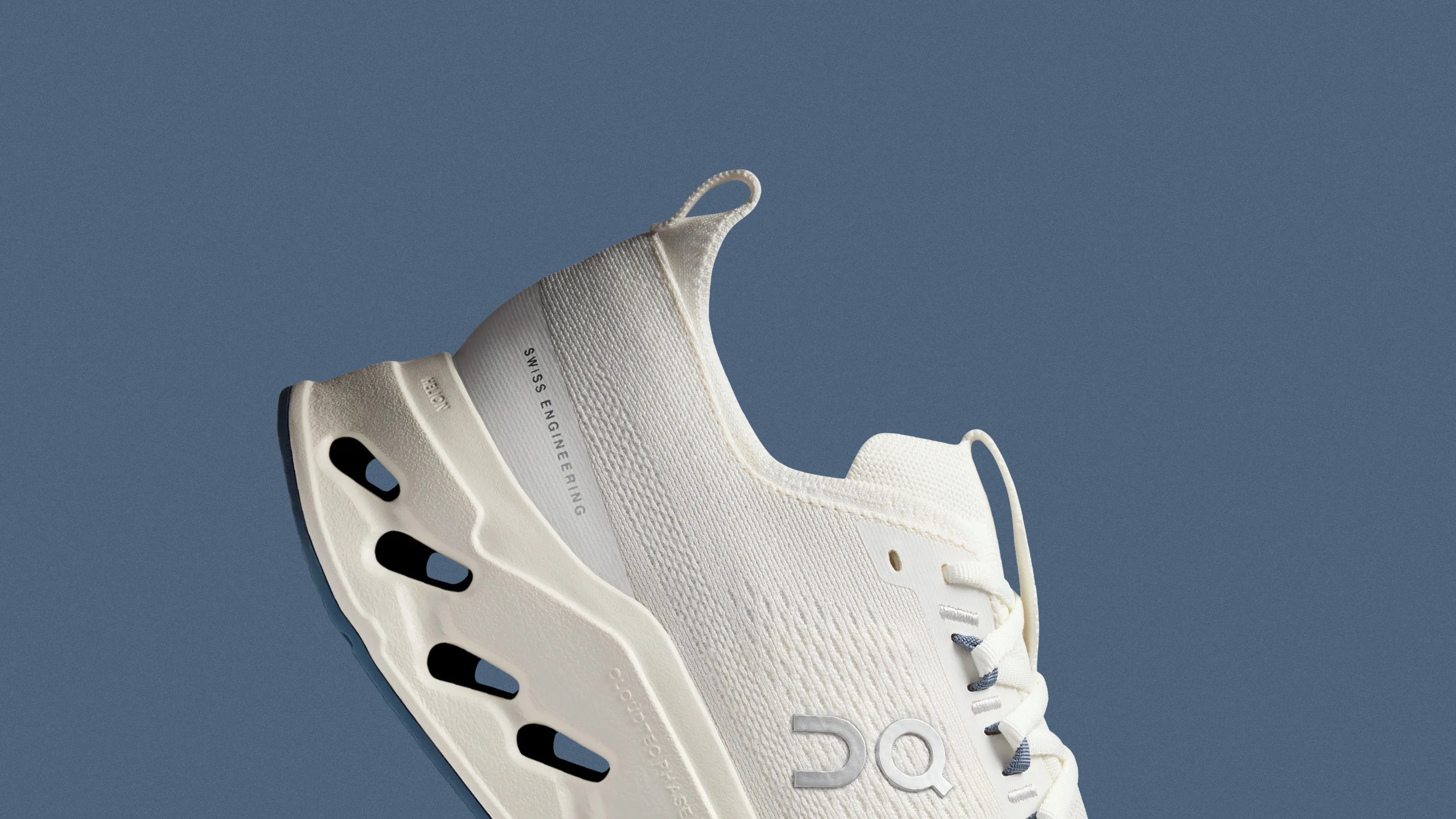 White athletic shoe with a textured sole featuring cut-out sections and "Swiss Engineering" text on the heel.