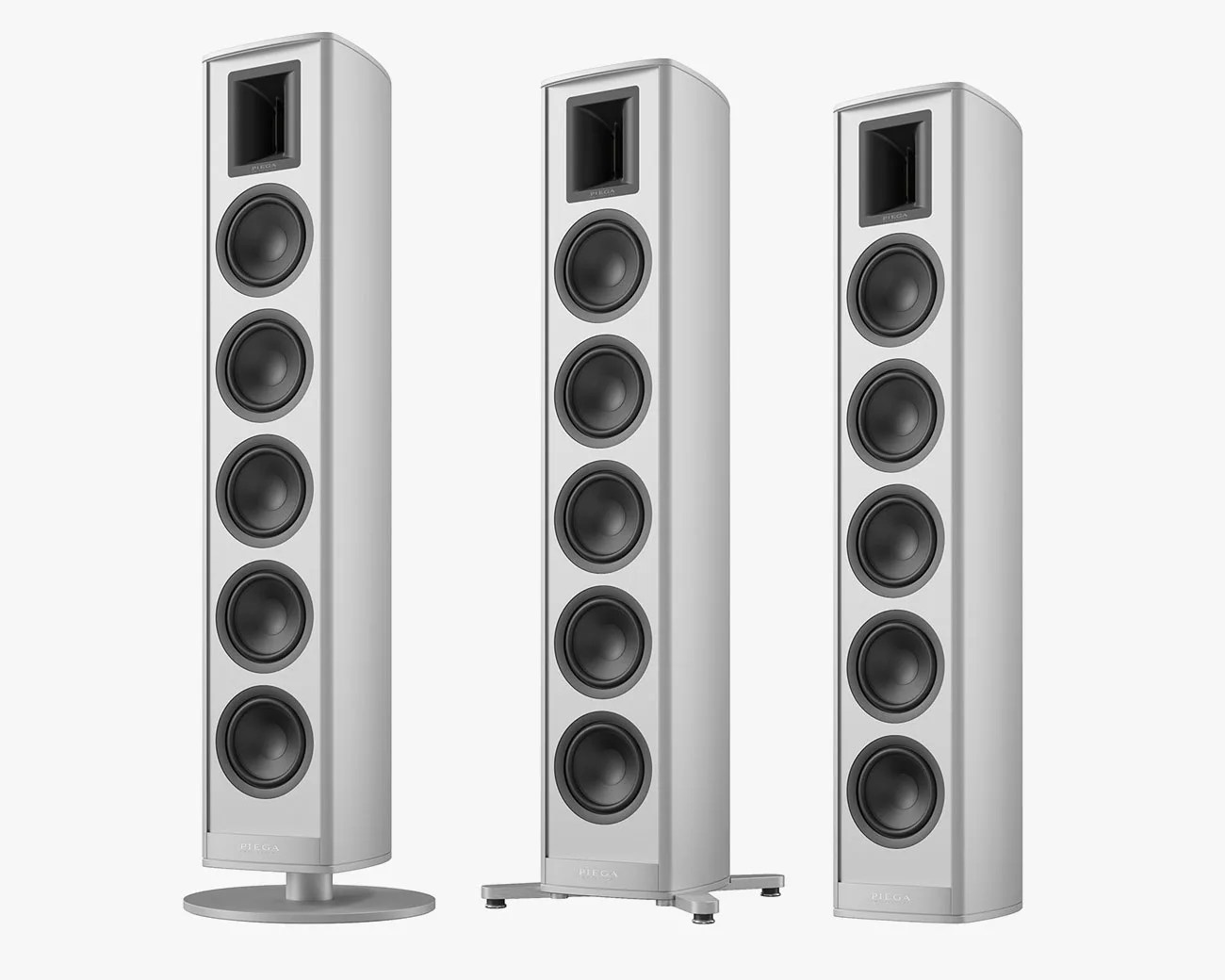 Three tall, white floor-standing speakers with four black drivers and a horn tweeter each, on different bases.