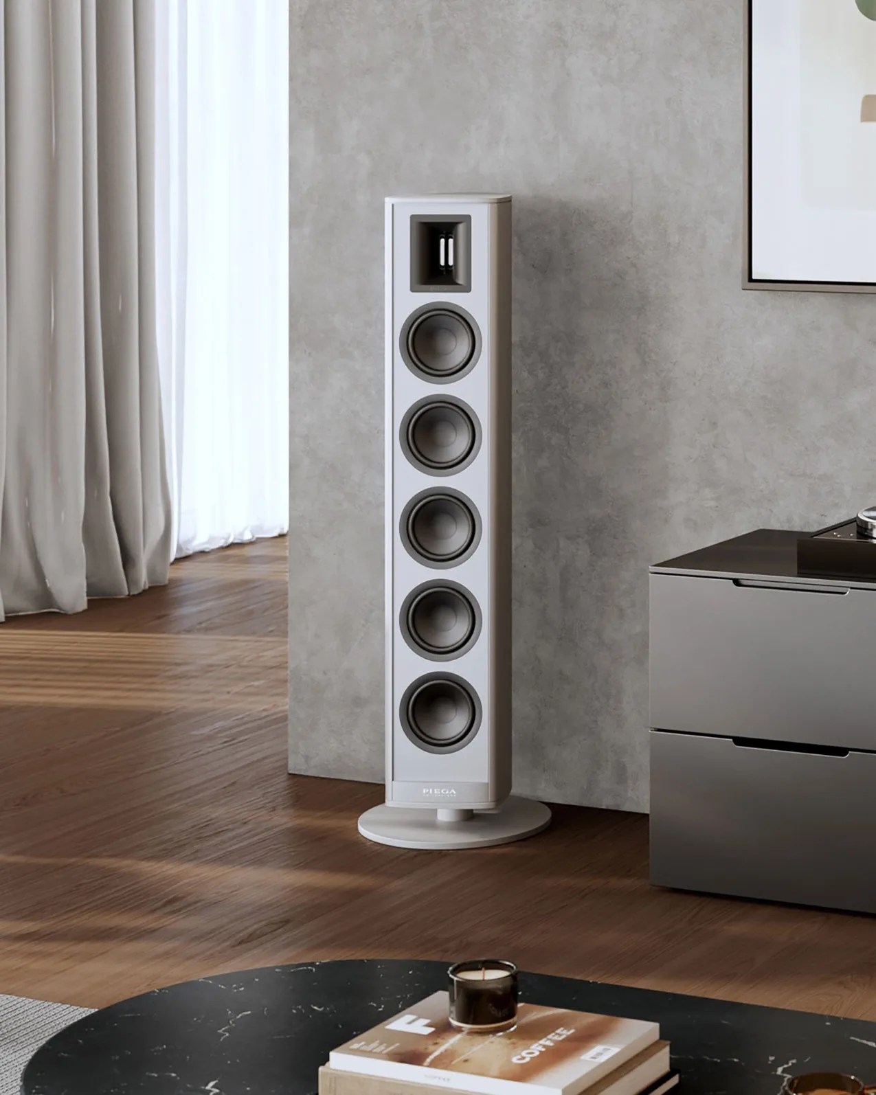 Tall white floor-standing speaker with five drivers on a wooden floor next to a gray cabinet.
