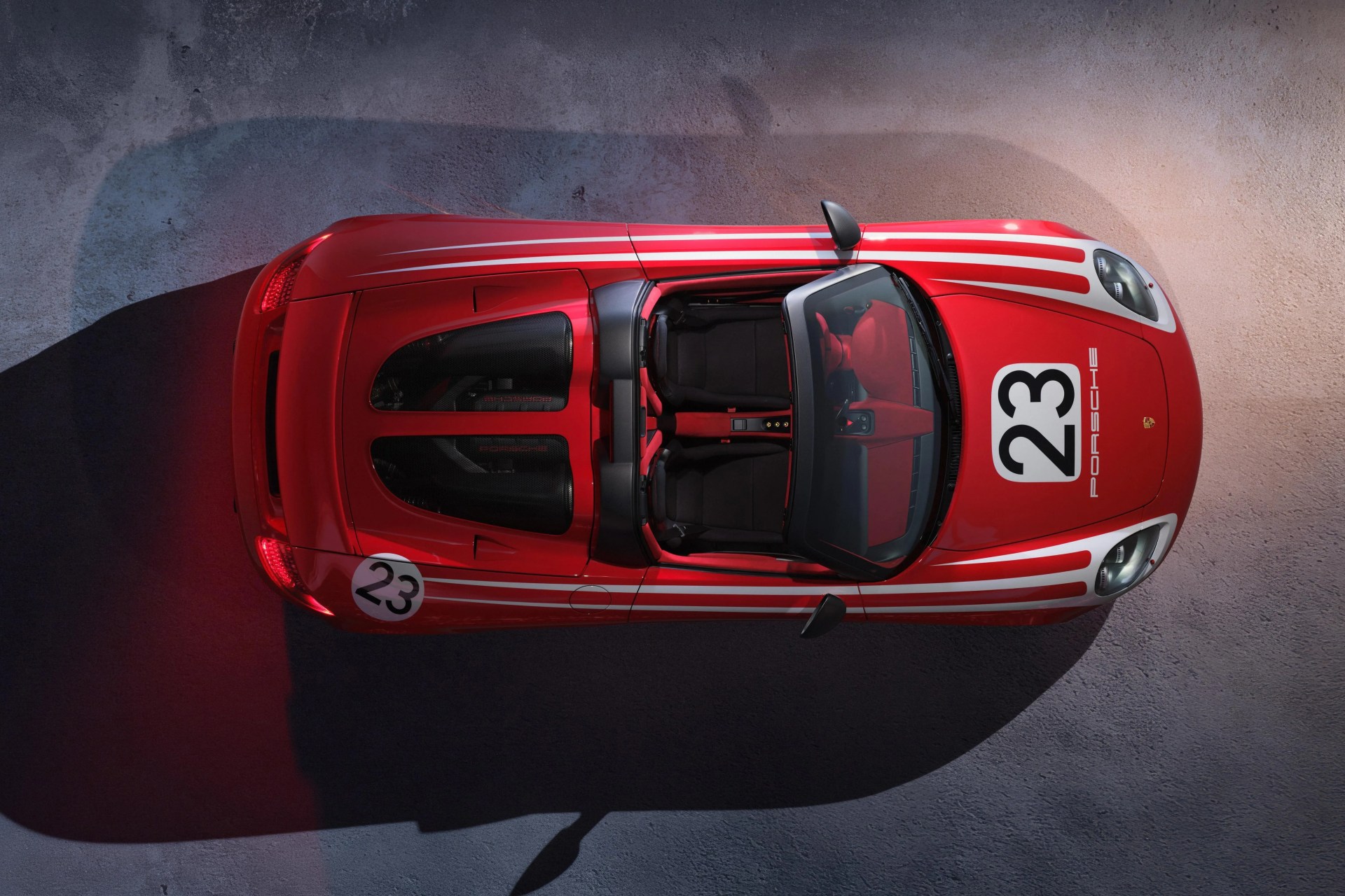 Red Porsche convertible race car with white racing stripes and number 23 decals, viewed from above.