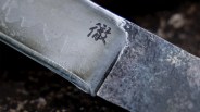 Close-up of a metal knife blade with a Japanese character engraved near the handle.