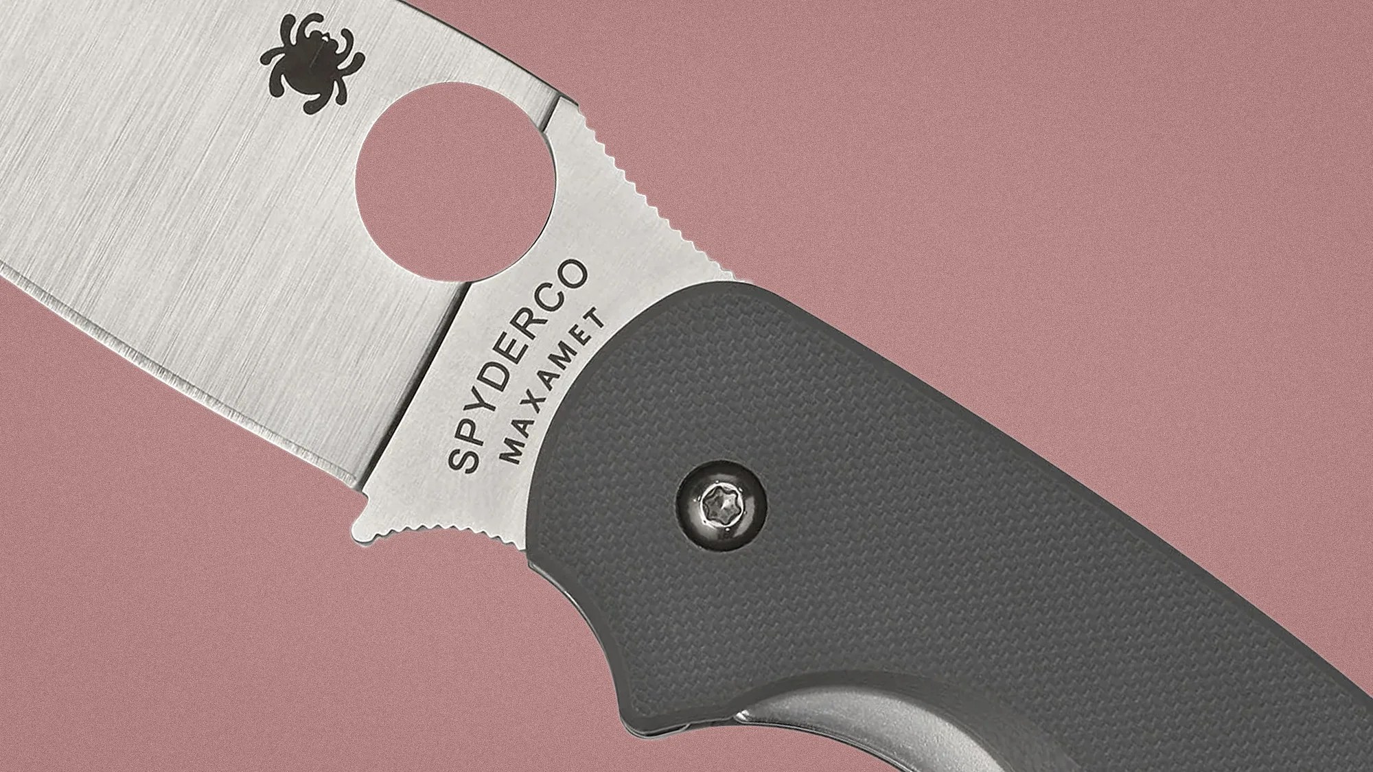Close-up of a Spyderco Maxamet folding knife blade with a round hole and textured dark gray handle.