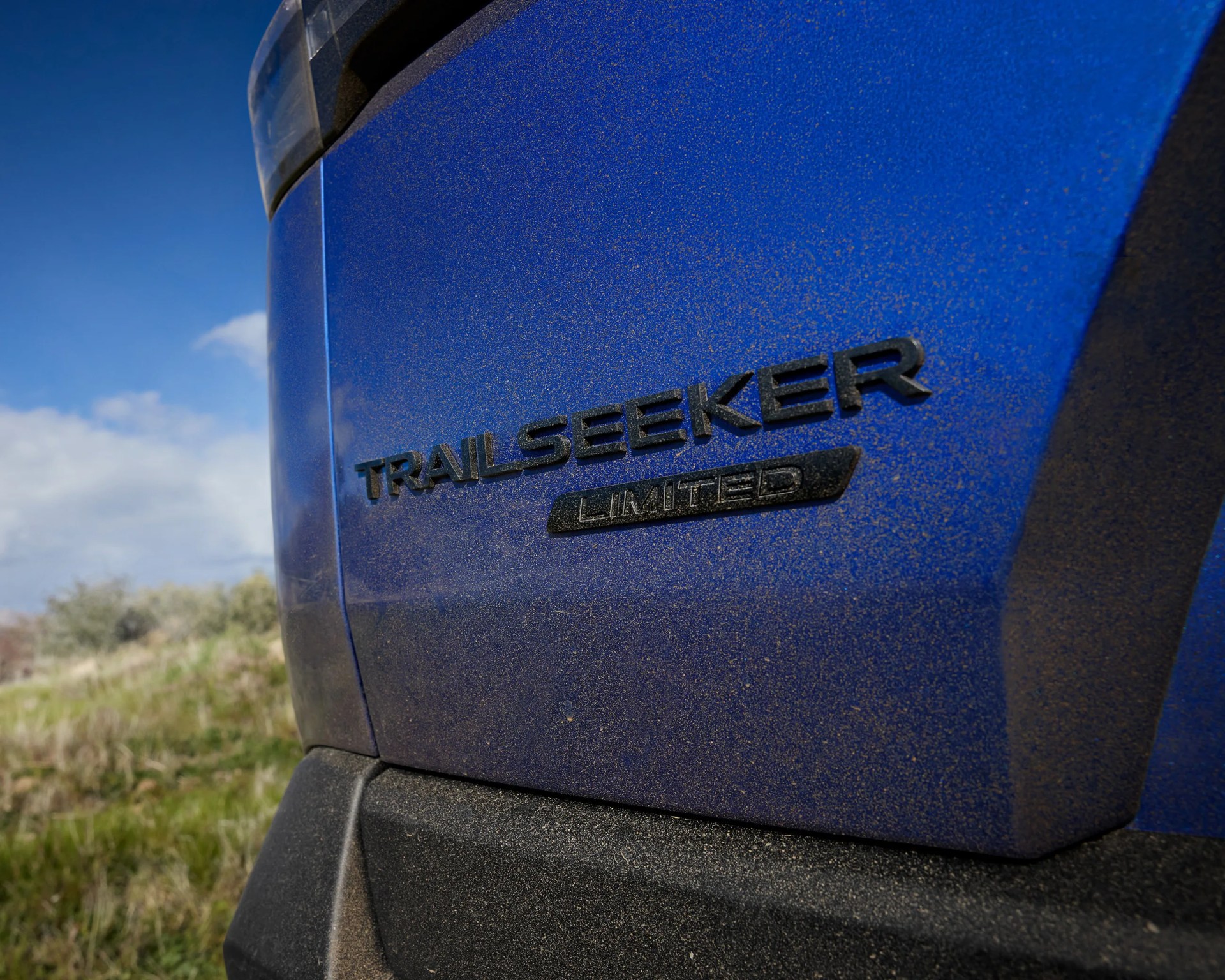 Close-up of a blue vehicle's rear with "TRAILSEEKER LIMITED" badge and dirt on the surface.