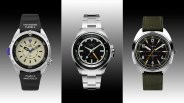 Three Timex wristwatches: left with black rubber strap and cream dial, center with silver metal bracelet and black dial, right with green fabric strap and black dial.