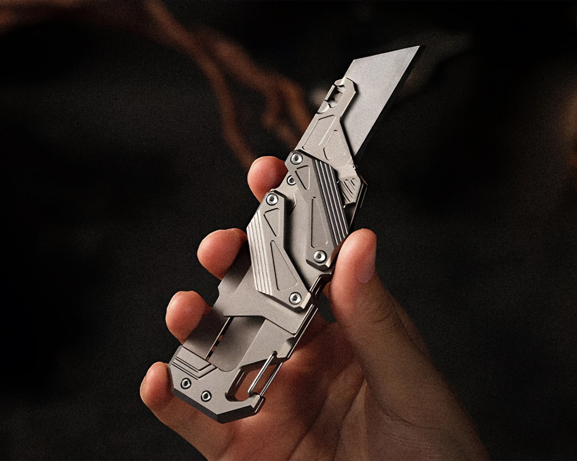 Hand holding a metallic multi-tool with a partially extended blade and geometric design.