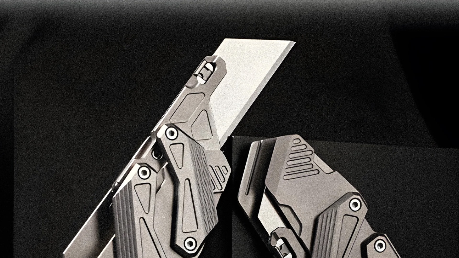 Close-up of two metallic folding knives with geometric designs on their handles against a dark background.