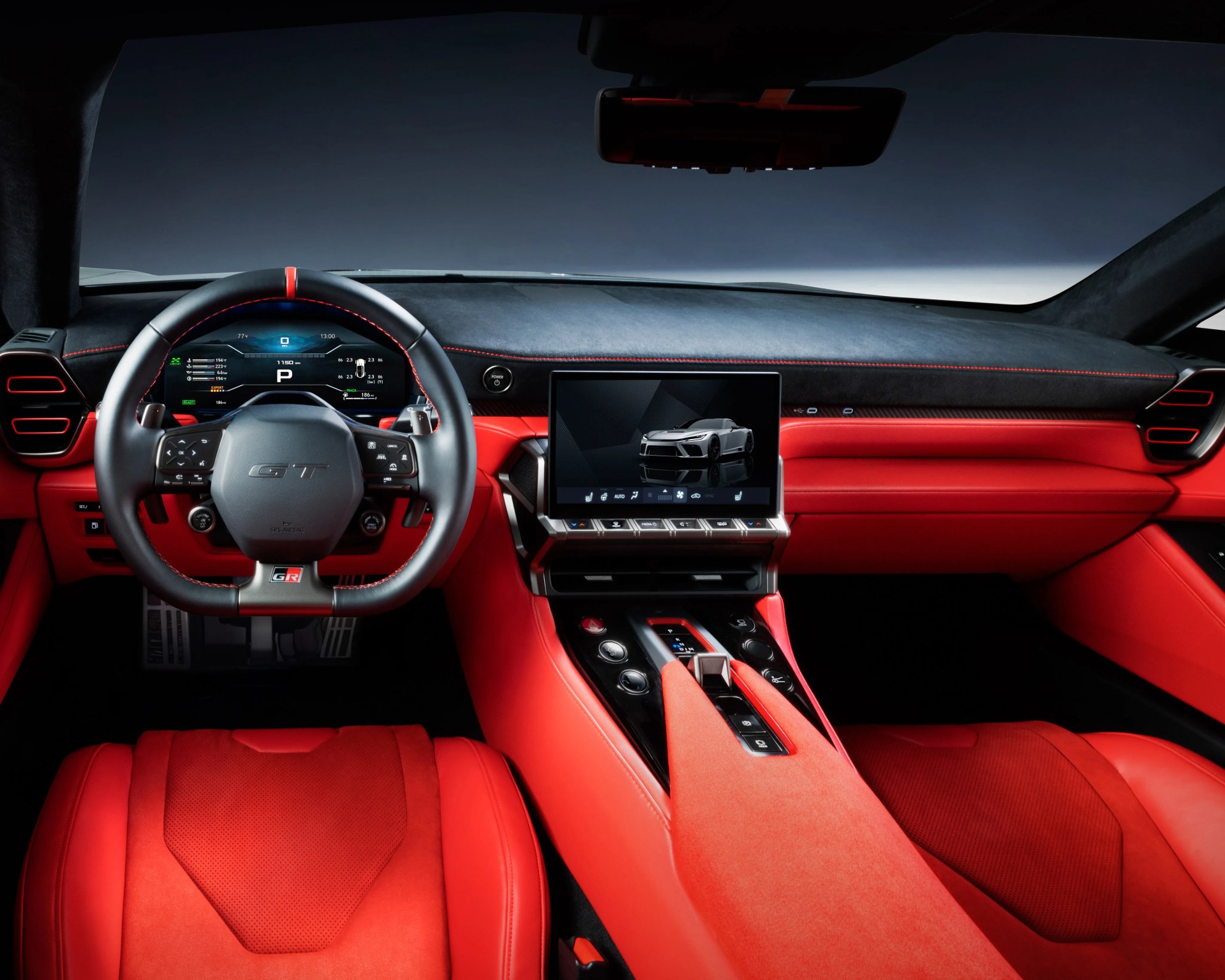 Red leather and Alcantara car interior with digital dashboard, touchscreen center console, and GT-branded steering wheel.