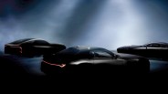 Three black sports cars with sleek designs and illuminated red rear lights in a dimly lit setting.