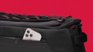 Black padded bag with red trim and a white smartphone partially visible in a side pocket.