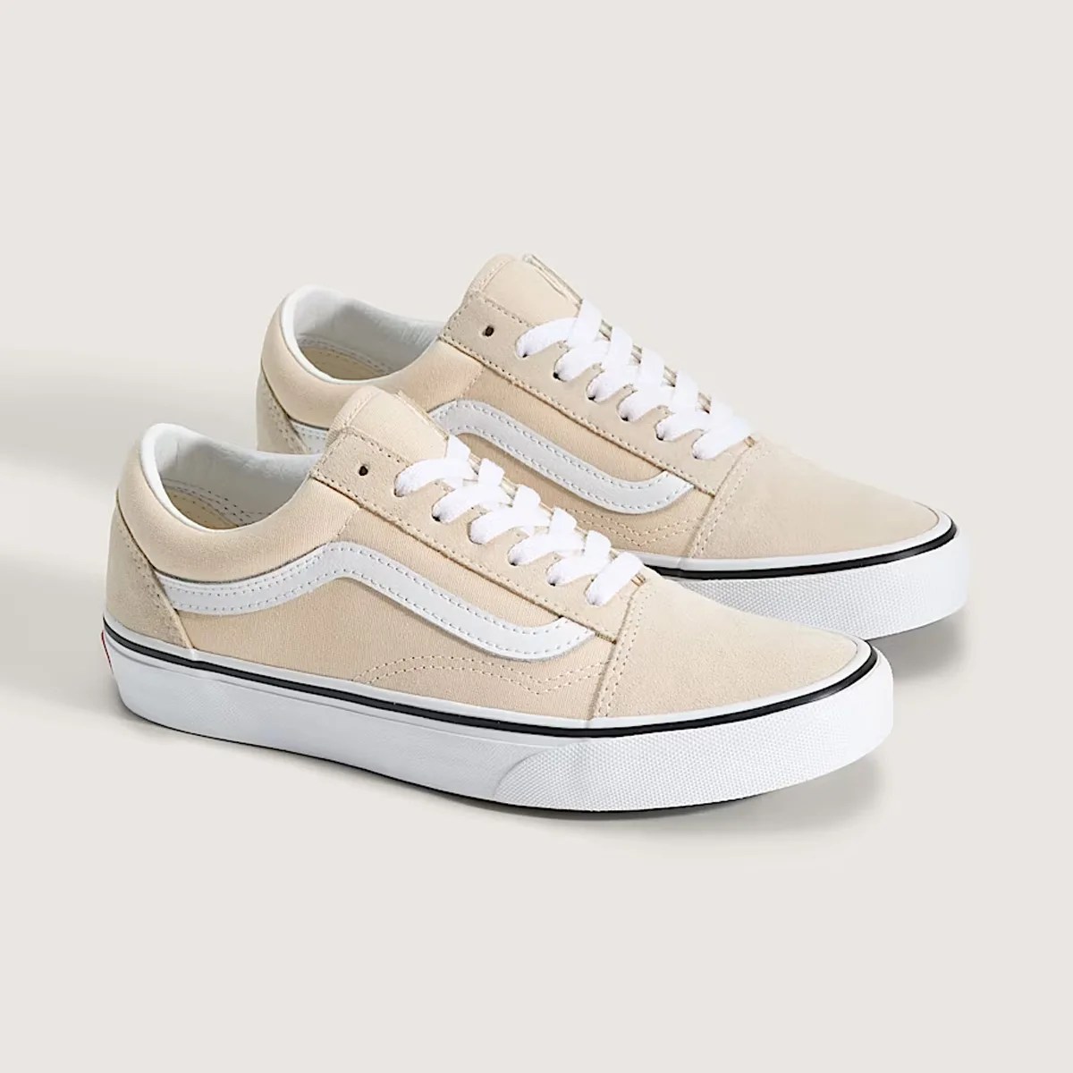 Pair of beige low-top Vans sneakers with white side stripe and white rubber soles.