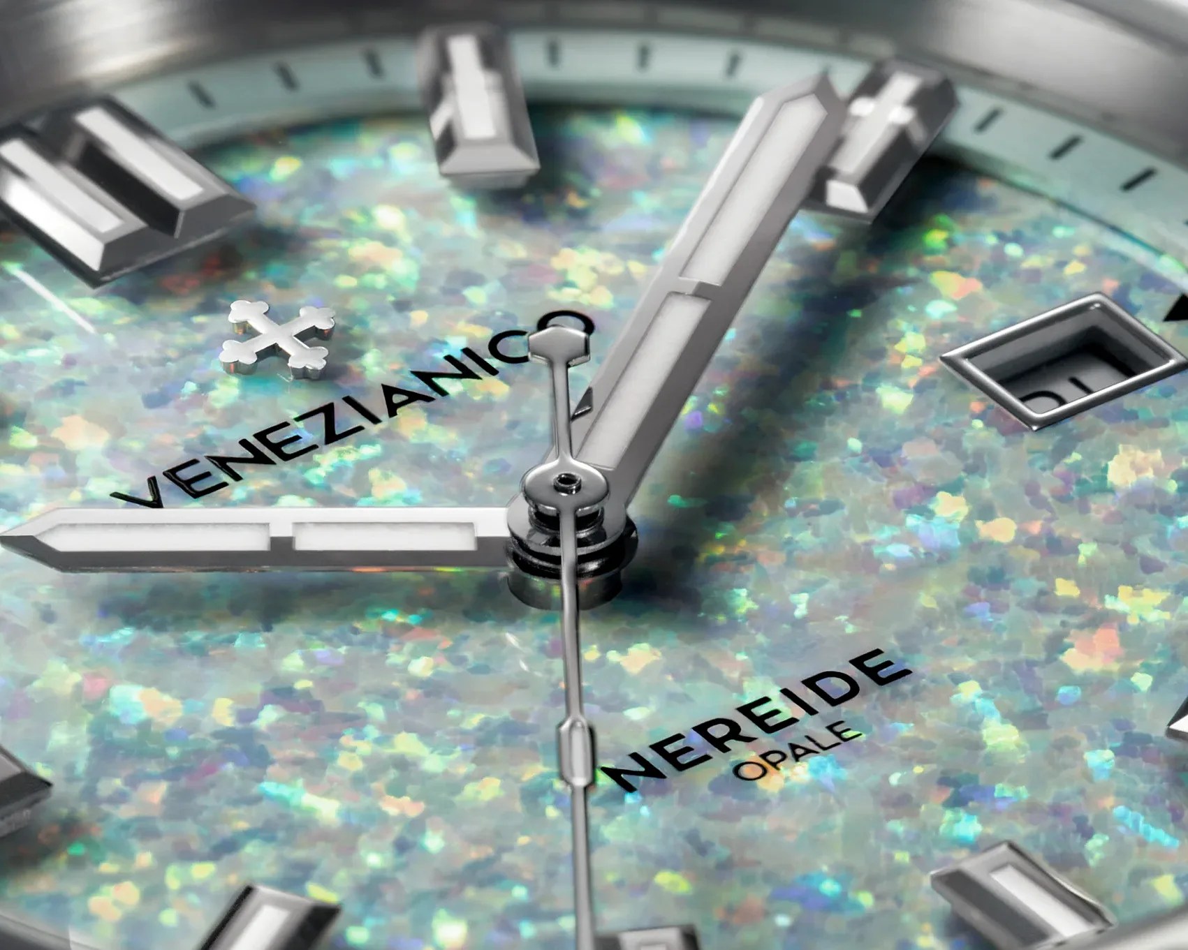 Close-up of a watch face with iridescent opal dial, silver hands, and the text "Venezianico" and "Nereide Opale.