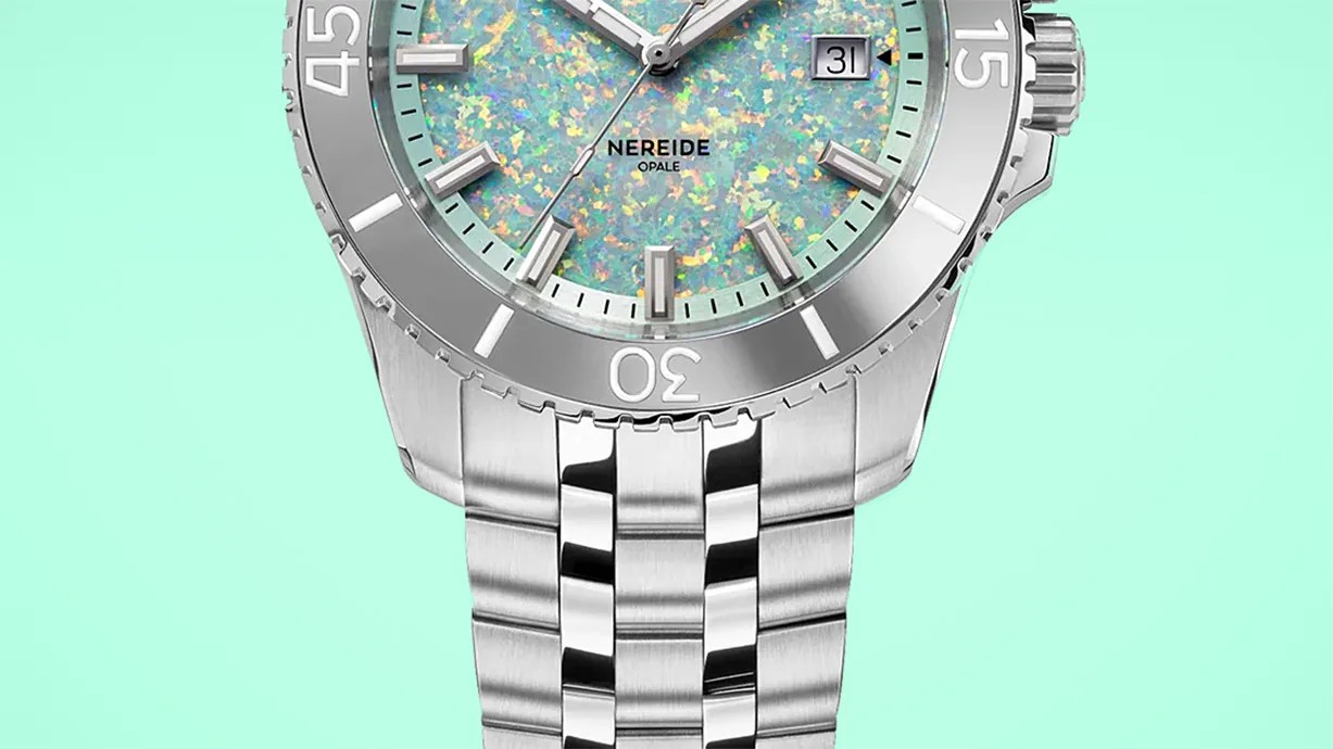 Silver metal wristwatch with a multicolored opal dial and date display on a mint green background.