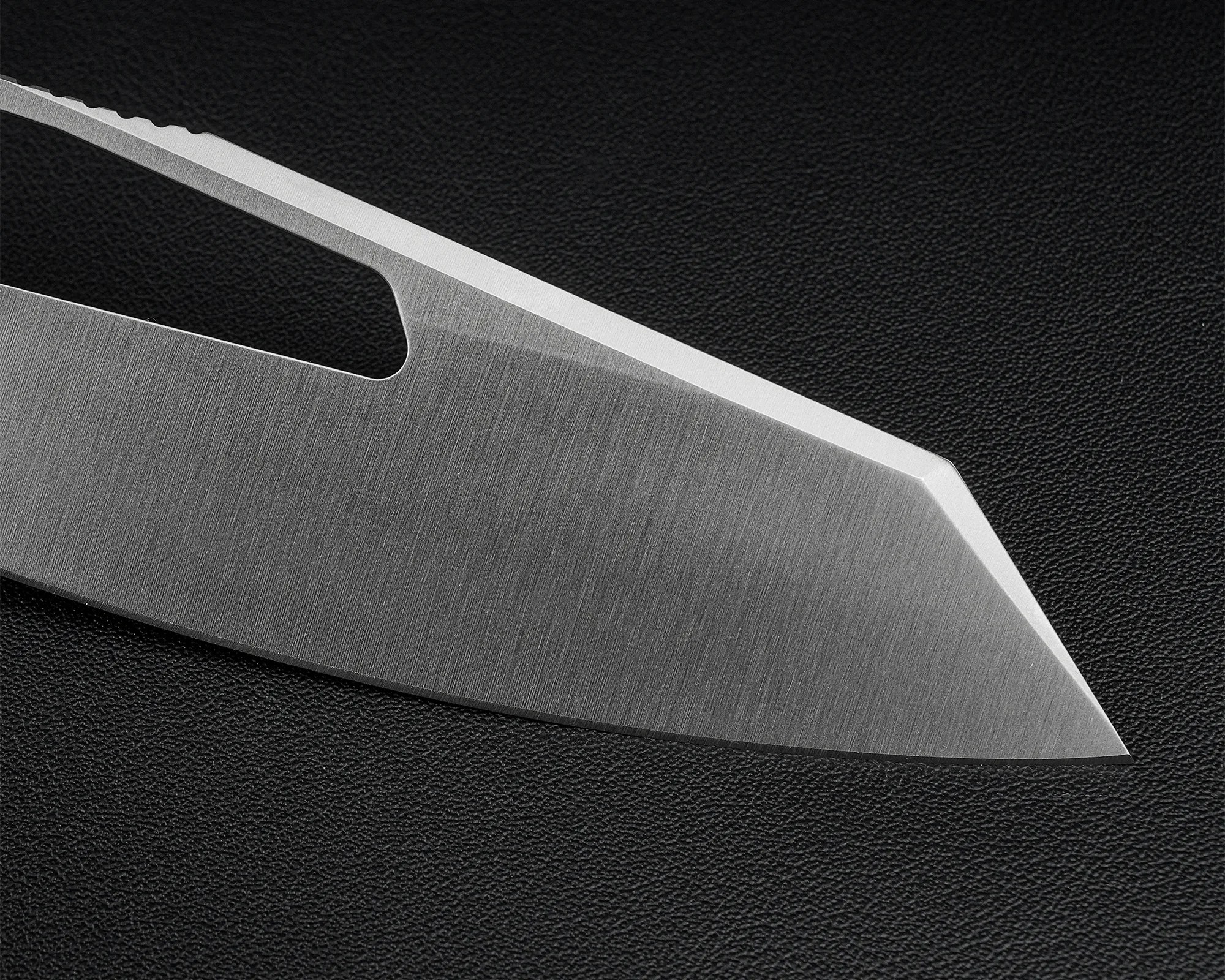 Close-up of a sharp, stainless steel knife blade with a textured black background.