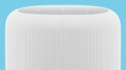 Close-up of a white smart speaker with mesh fabric exterior and touch controls on top against a blue background.