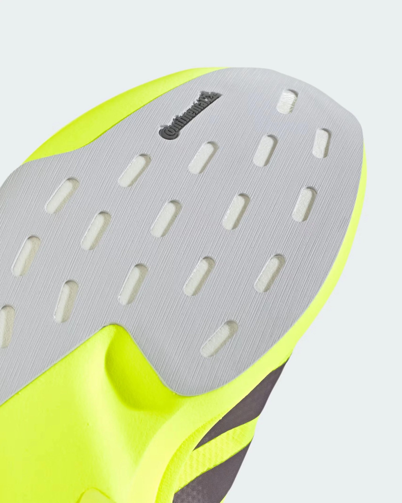 Close-up of a neon yellow shoe sole with a gray textured outsole featuring rectangular cutouts and a Continental logo.