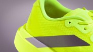 Close-up of a neon yellow athletic shoe with textured fabric and a black diagonal stripe on the side.